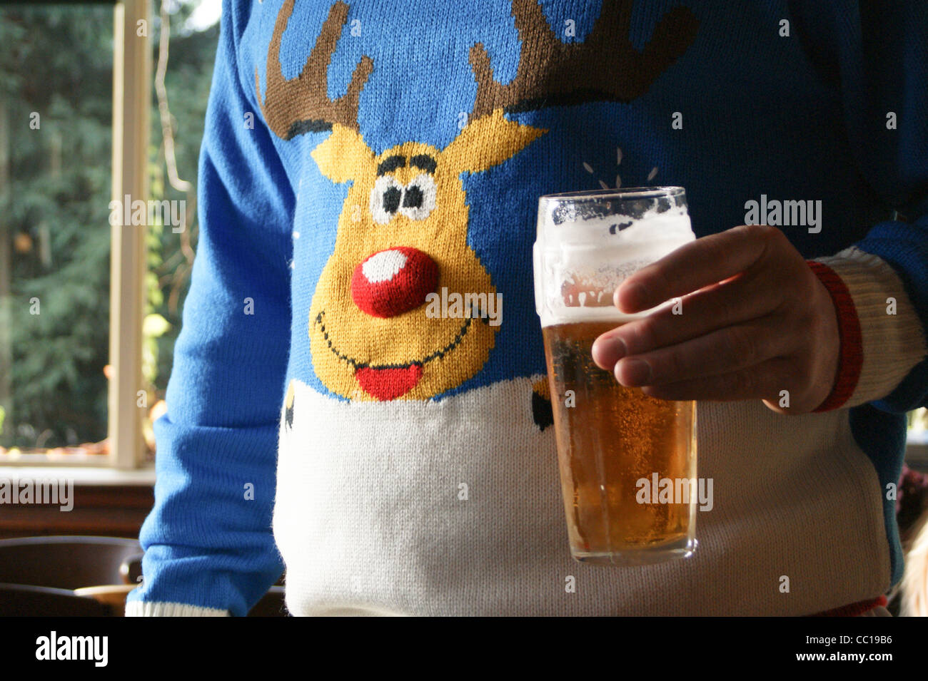 Un uomo con una pinta di favorisce la birra chiara in un ponticello di Natale con un modello di renne a Warren pub in legno, Buckhurst Hill, Essex, Inghilterra Foto Stock Un uomo con una pinta di favorisce la birra chiara in un ponticello di Natale con un modello di renne a Warren pub in legno, Buckhurst Hill, Essex, Inghilterra Foto Stock