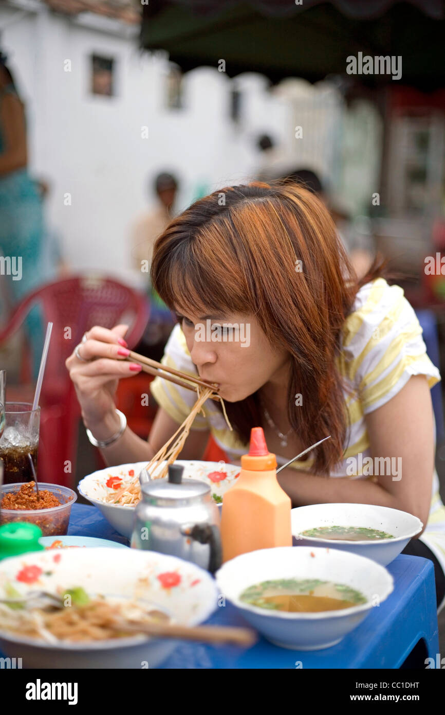 Una donna mangia Pho noodle soup per colazione in corrispondenza di un lato della strada cafe, Ho Chi Minh City (ex Saigon), Vietnam Foto Stock