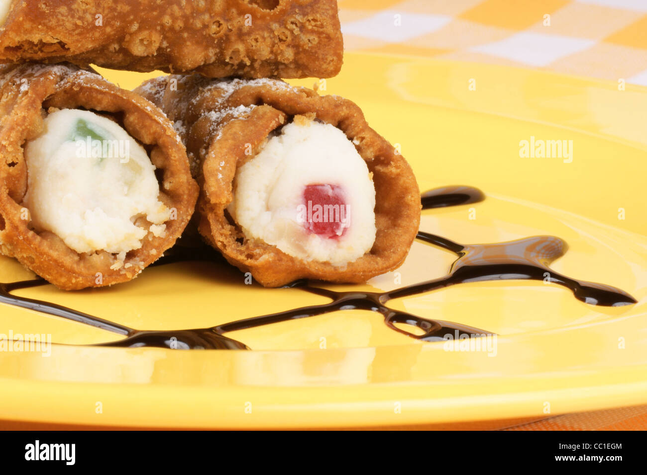 Close-up di originale mini cannoli siciliani su una piastra di colore giallo. Foto Stock