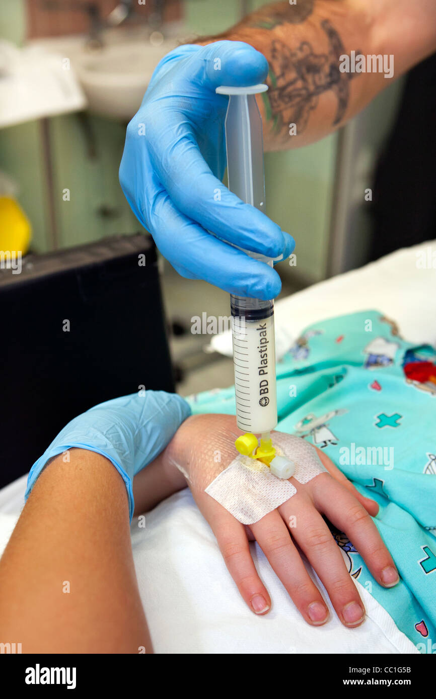 Anestesista iniettare la sostanza anestetica attraverso una cannula venosa prima di intervento chirurgico Foto Stock