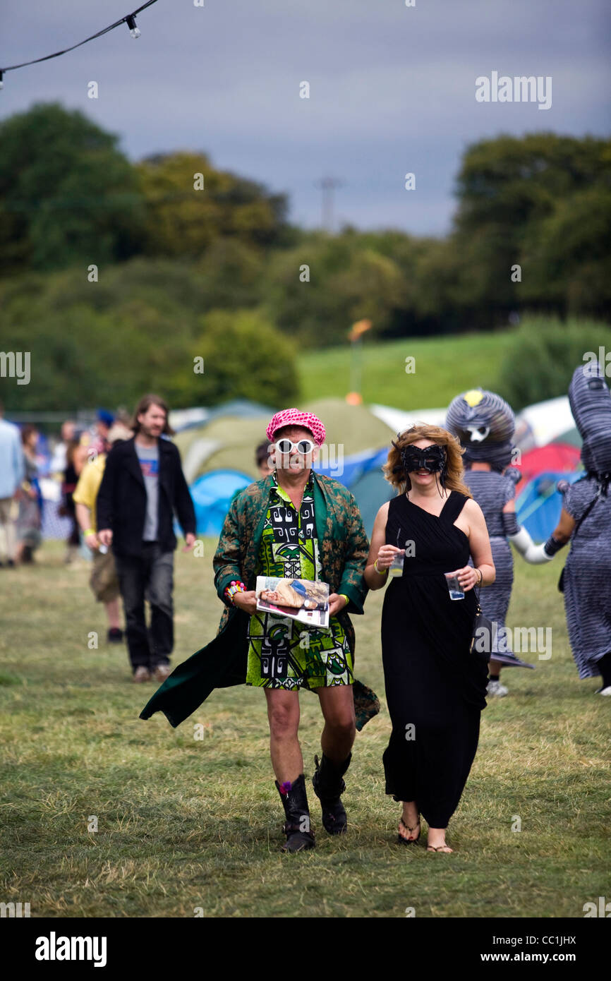 Un uomo e una donna in costume a piedi attraverso un campo a Standon Calling Festival nel Hertfordshire, Regno Unito Foto Stock