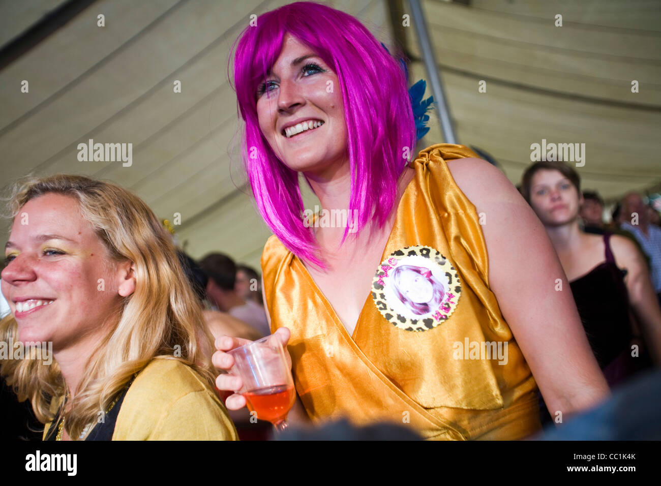 Una donna in una parrucca viola con un drink sorrisi come ella