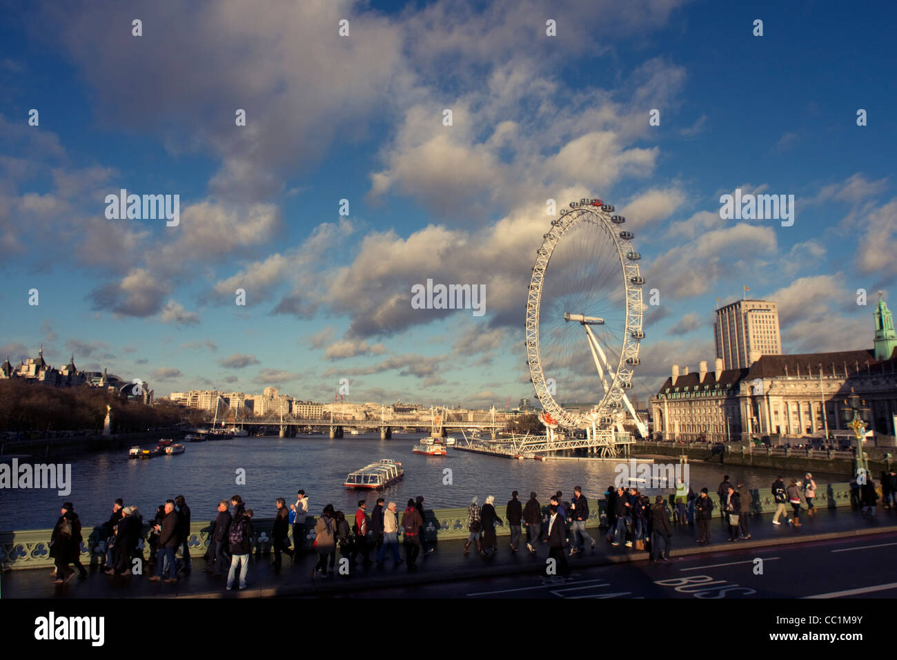Vista sul Fiume Tamigi e il London Eye e pedoni camminando lungo il Westminster Bridge, London, England, Regno Unito Foto Stock