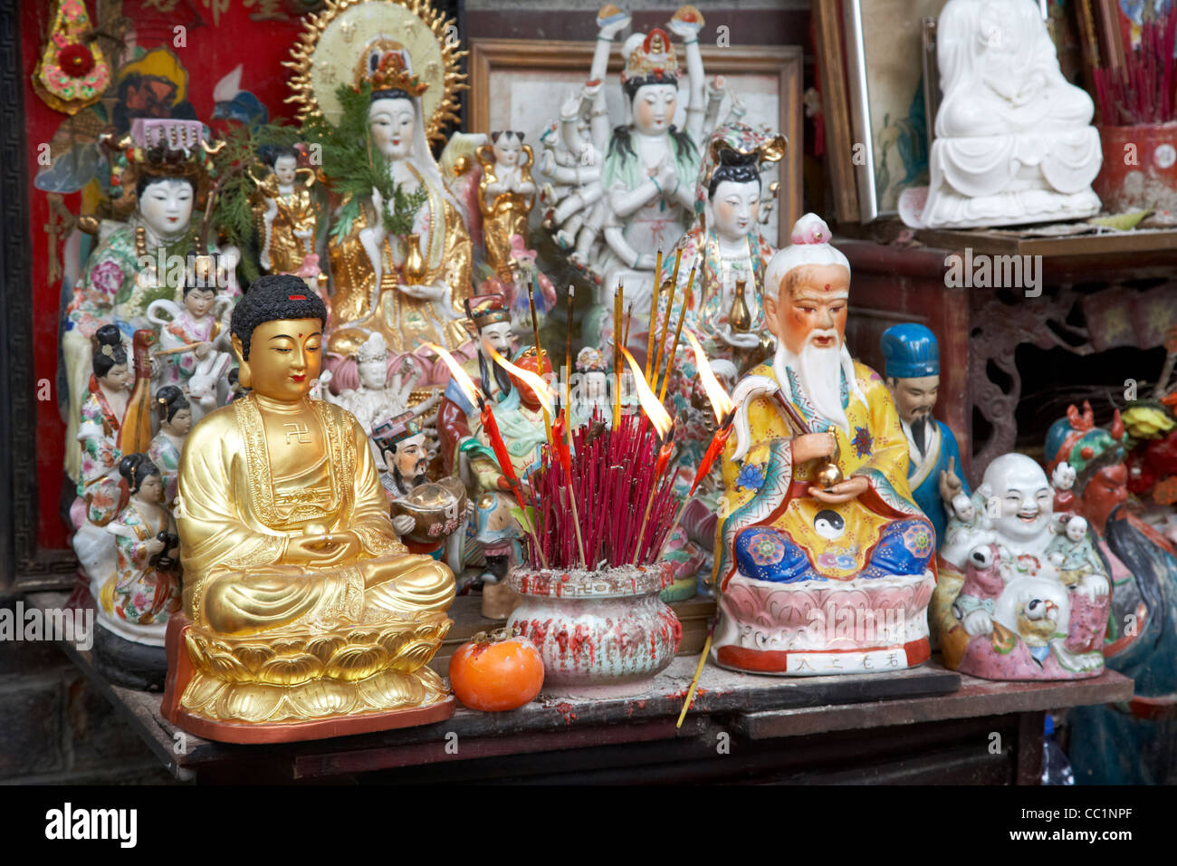 Bruciare incenso e offerte di cibo al piccolo santuario si affacciava sulla strada al di fuori di un tempio di hong kong RAS di Hong kong cina asia Foto Stock