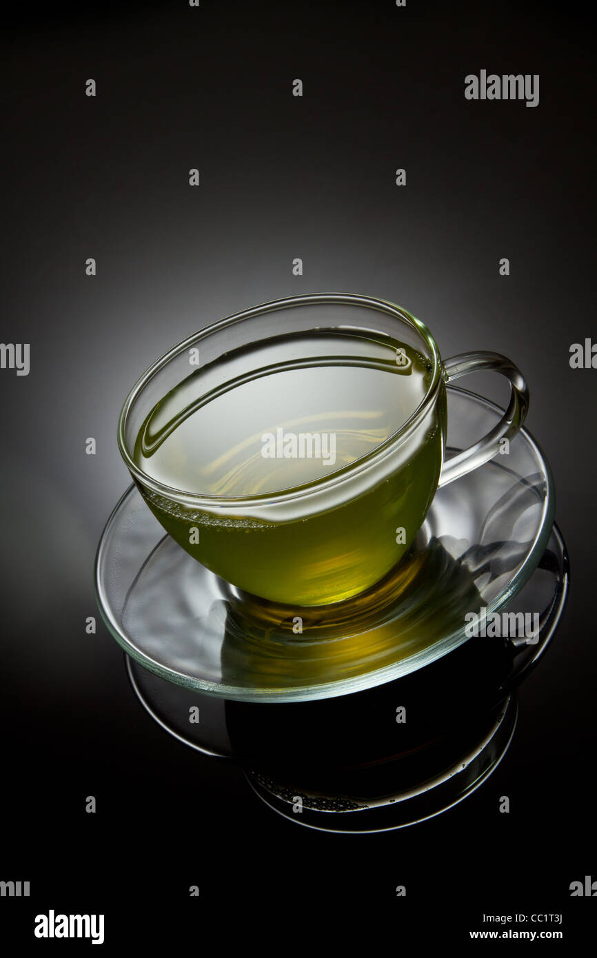 Il tè verde nella coppa di vetro su uno sfondo grigio Foto Stock