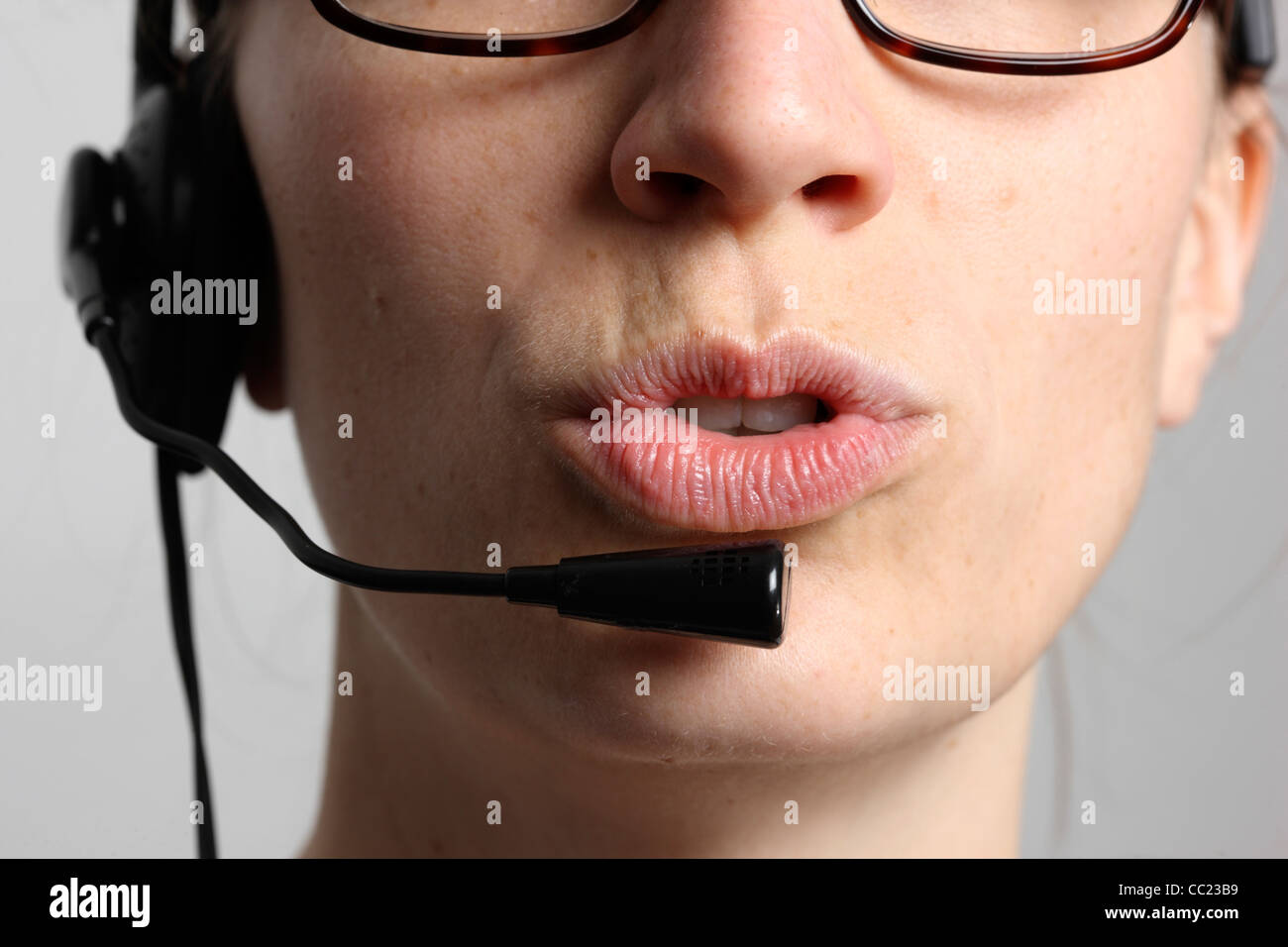 Giovane donna sta parlando, sul telefono, Internet Voice over IP, utilizzando un auricolare. Primo piano del volto. Foto Stock