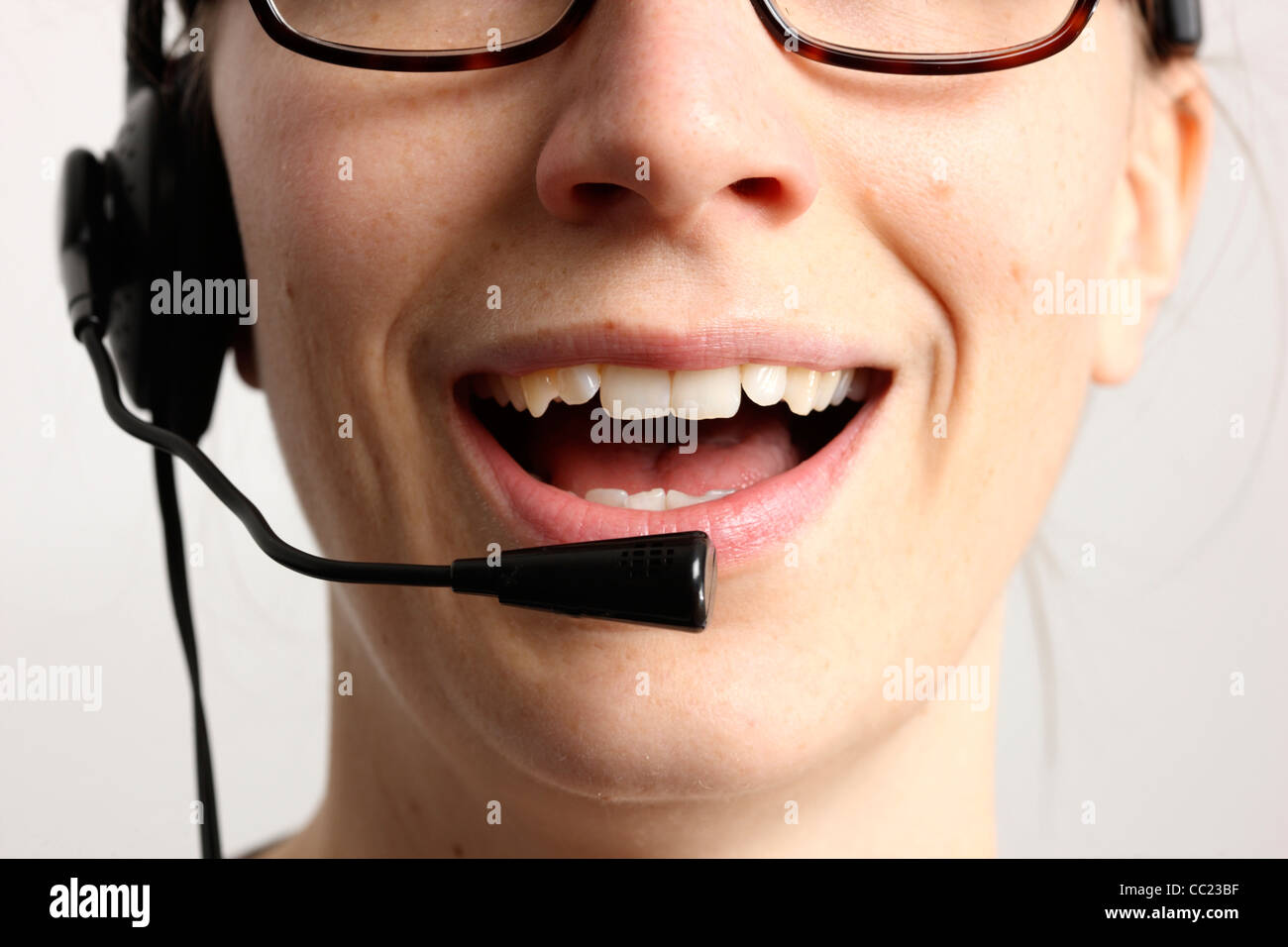 Giovane donna sta parlando, sul telefono, Internet Voice over IP, utilizzando un auricolare. Primo piano del volto. Foto Stock