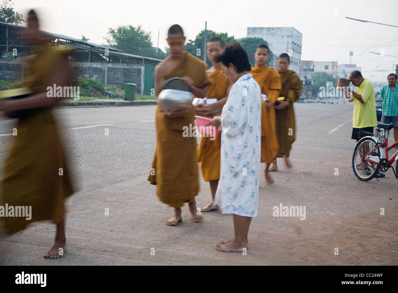 Monaci ricevono la mattina alms dalla Tailandese buddisti di rendere merito per le strade di Nakhon Phnom, Nakhon Phnom provincia, Thailandia Foto Stock