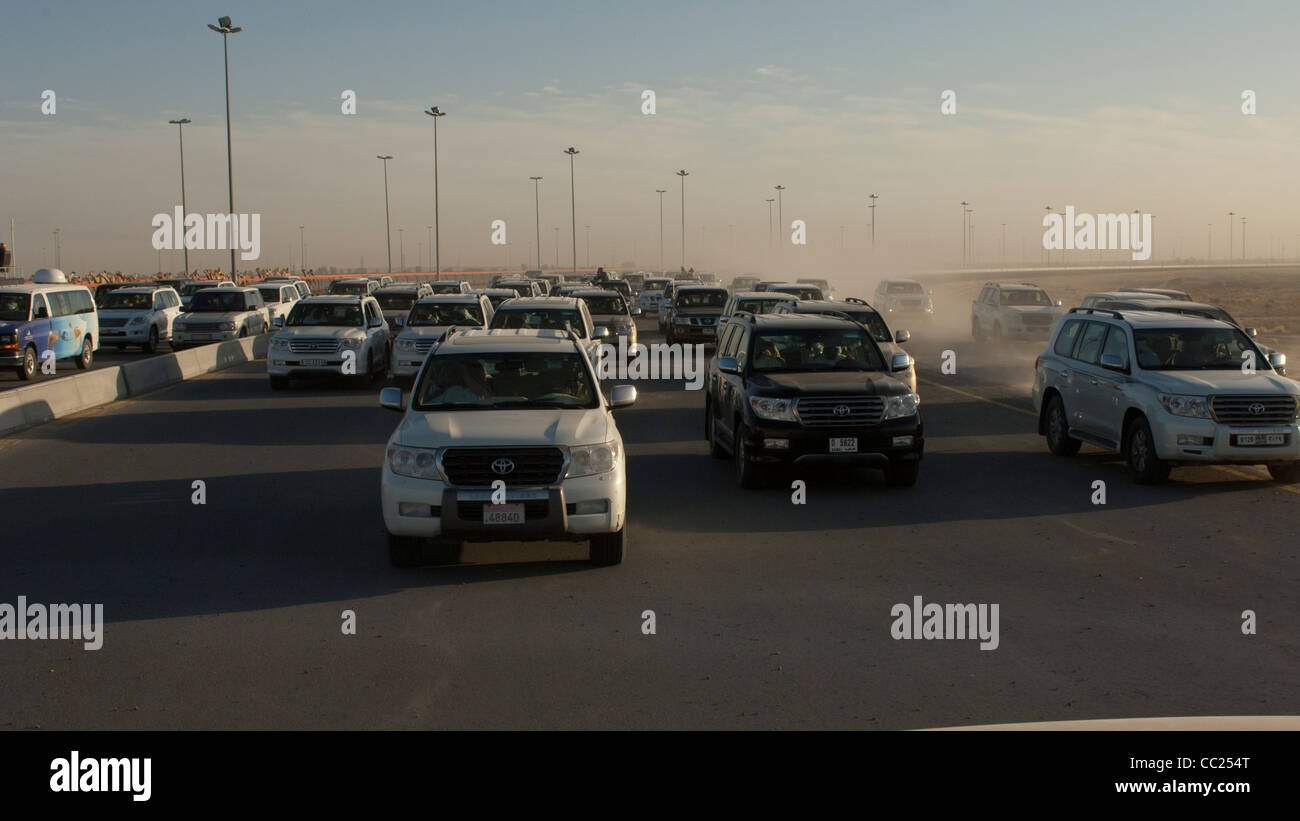 I proprietari e i formatori in SUV seguire le corse di cammelli in Dubai. Foto Stock