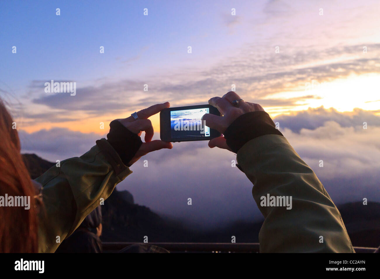 Visitatore visualizza scena attraverso lo schermo LCD e il sunrise fotografie con la fotocamera digitale al Cratere Haleakala, Maui, Hawaii, Stati Uniti d'America. Foto Stock