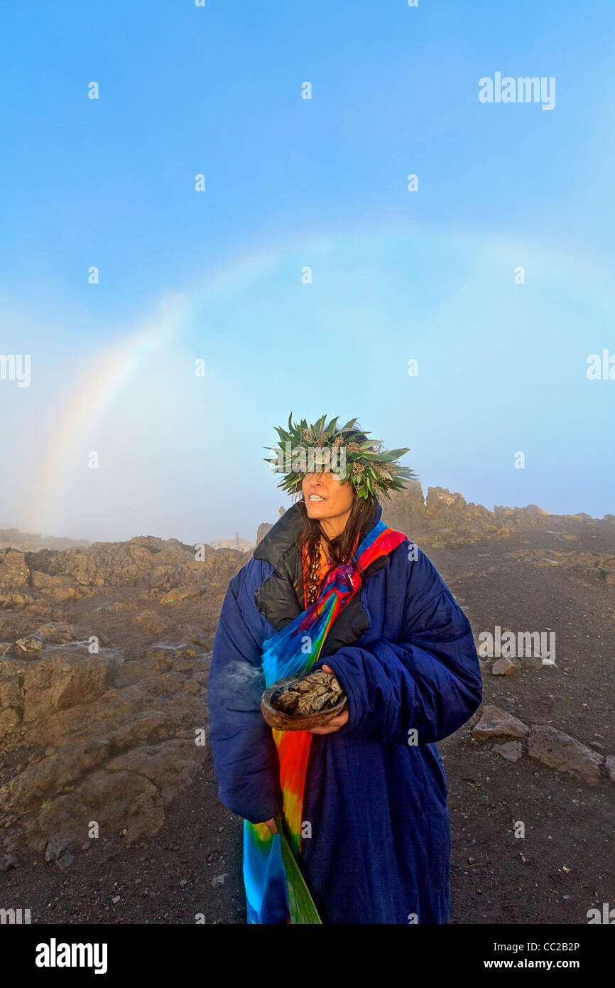 Barbara Bohonu, spirituale e culturale guaritore godendo un arcobaleno poco dopo l'alba al Cratere Haleakala, Maui, Hawaii, Stati Uniti d'America. Foto Stock