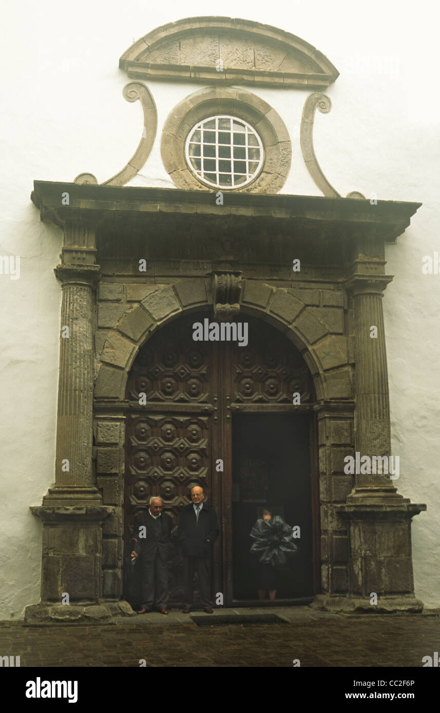 La gente si ripara dalla pioggia alla porta della chiesa di San Marco, Icod de Los Vinos, Tenerife, Isole Canarie, Spagna Foto Stock