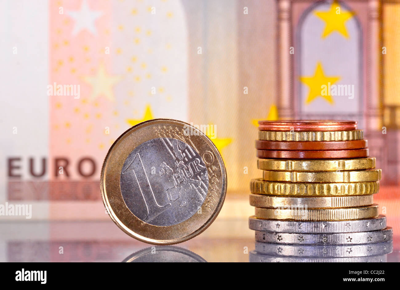 Un Euro moneta, accanto a una pila di monete con un 50 euro bill dietro Foto Stock