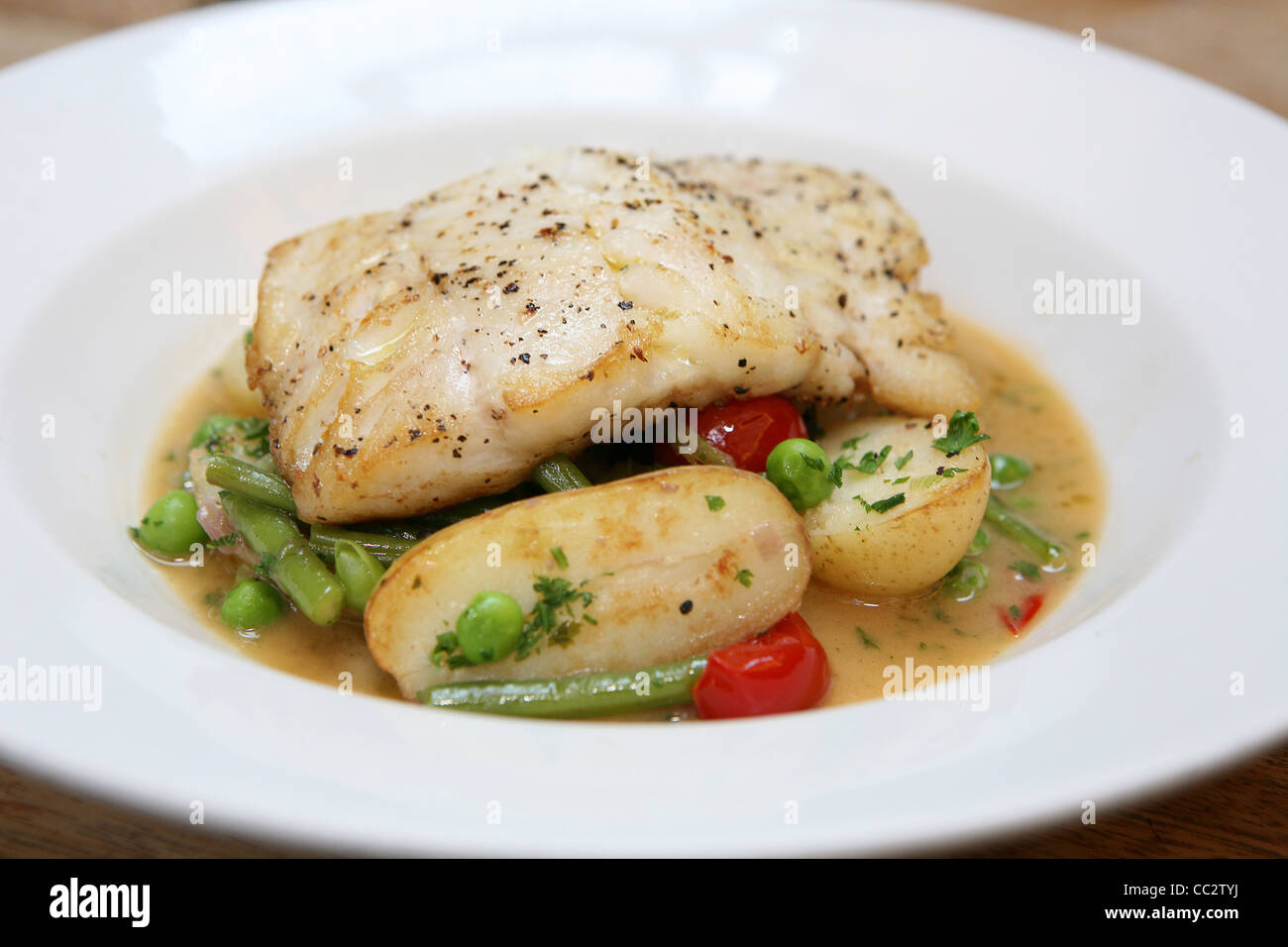 Piatto di pesce con patate pomodori Fagiolini e piselli Foto Stock