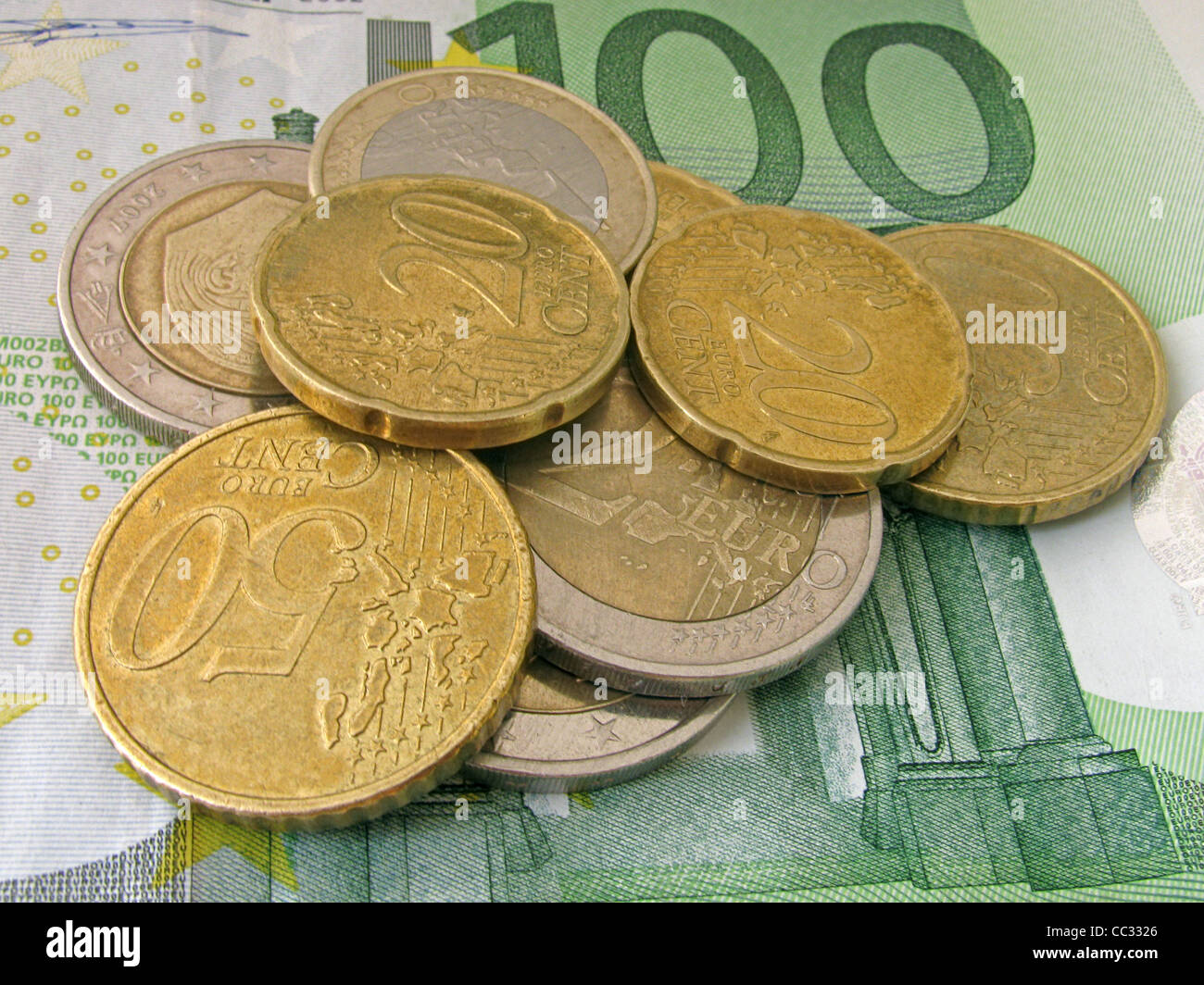 Cumulo di monete su un centinaio di banconote in euro Foto Stock