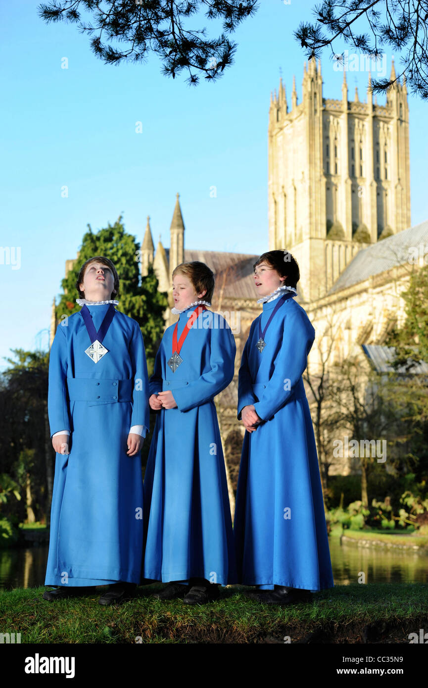 Tre boy coristi dalla Cattedrale di Wells coro in Somerset ripassando all'aperto per Natale carol servizi tramite "pozzi" Foto Stock