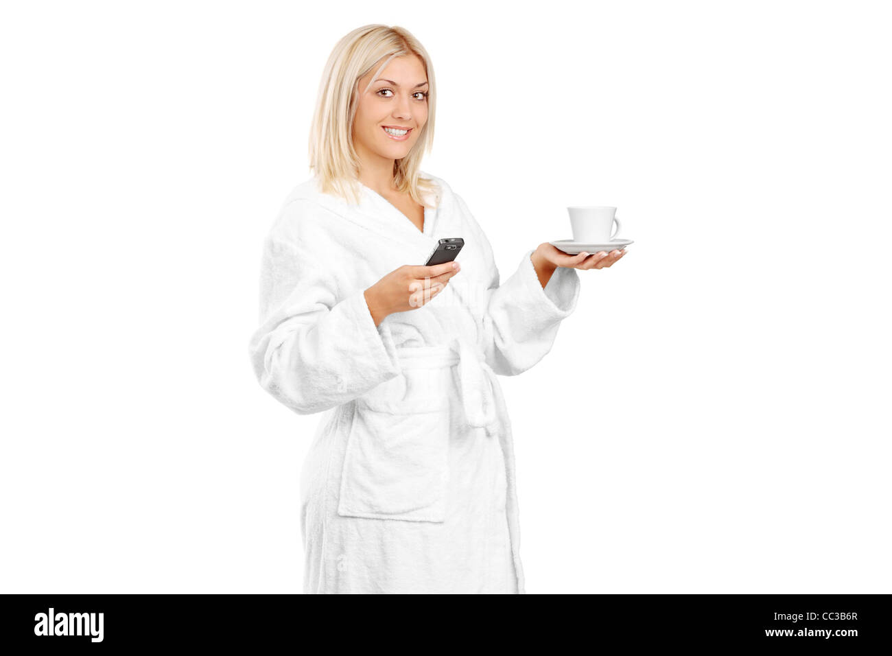 A piena lunghezza Ritratto di una giovane donna in accappatoio tenendo una tazza di caffè e telefono cellulare Foto Stock