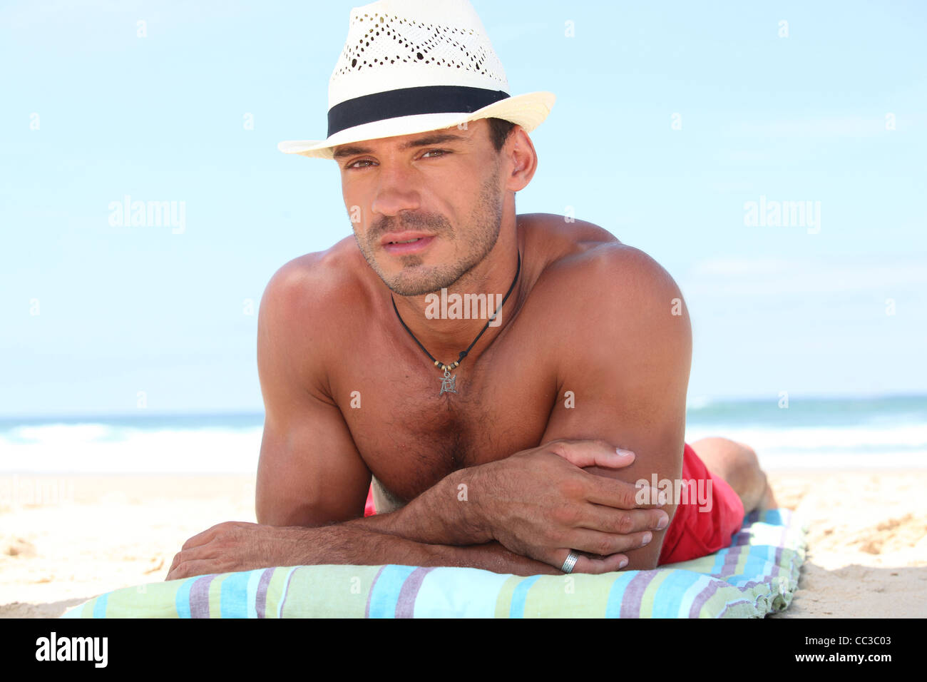 Uomo disteso sulla spiaggia in un cappello di paglia Foto stock - Alamy