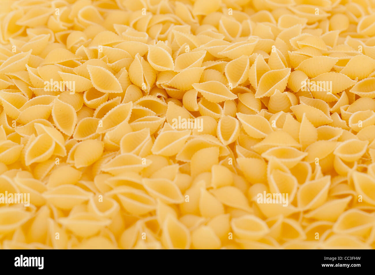 Asciugare la pasta gialla gusci (conchiglioni) come sfondo Foto Stock