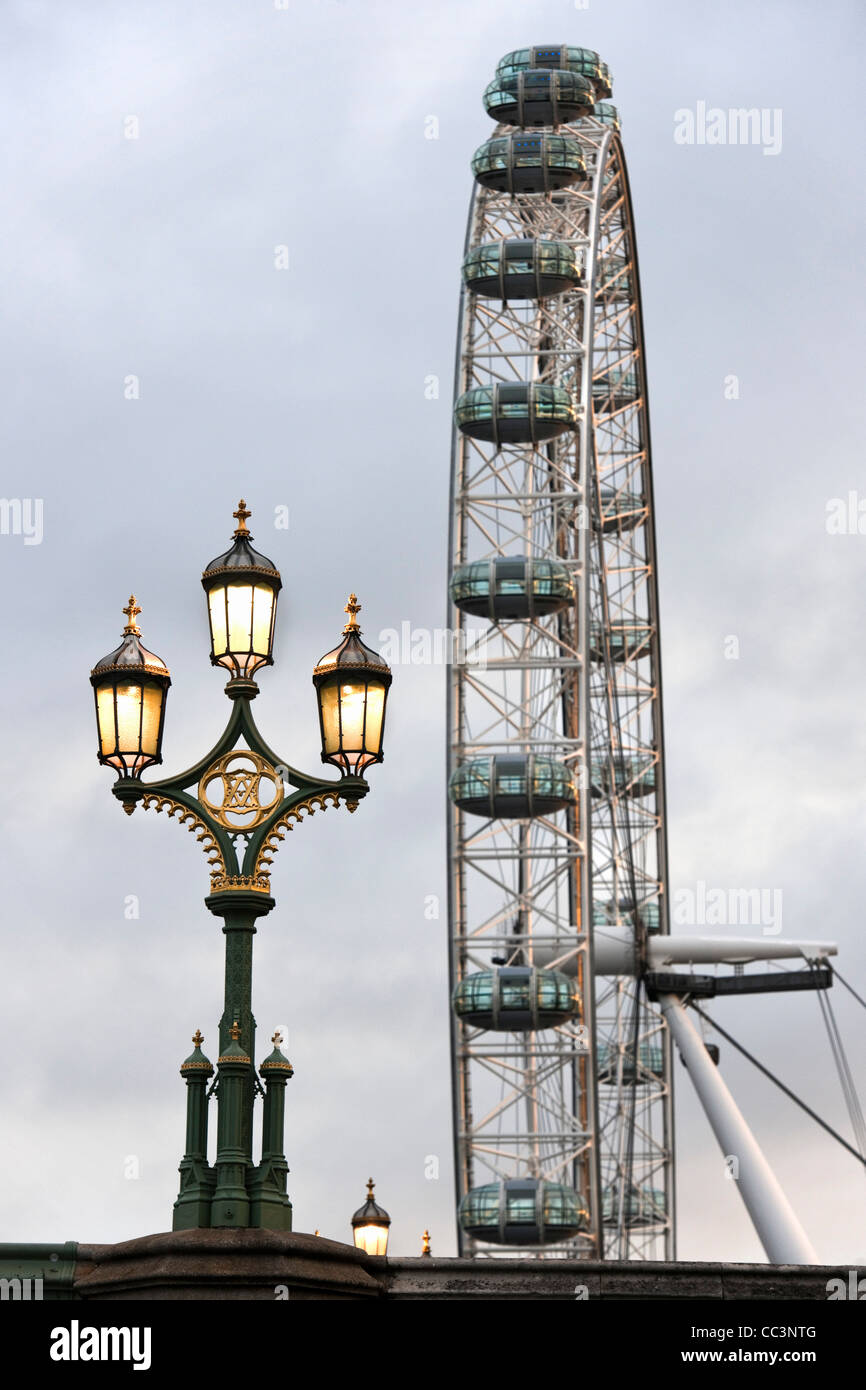 Il London Eye visto dal Westminster Bridge guardando ad Est all'alba con lampade in stile vittoriano in primo piano.Londra Inghilterra REGNO UNITO Foto Stock