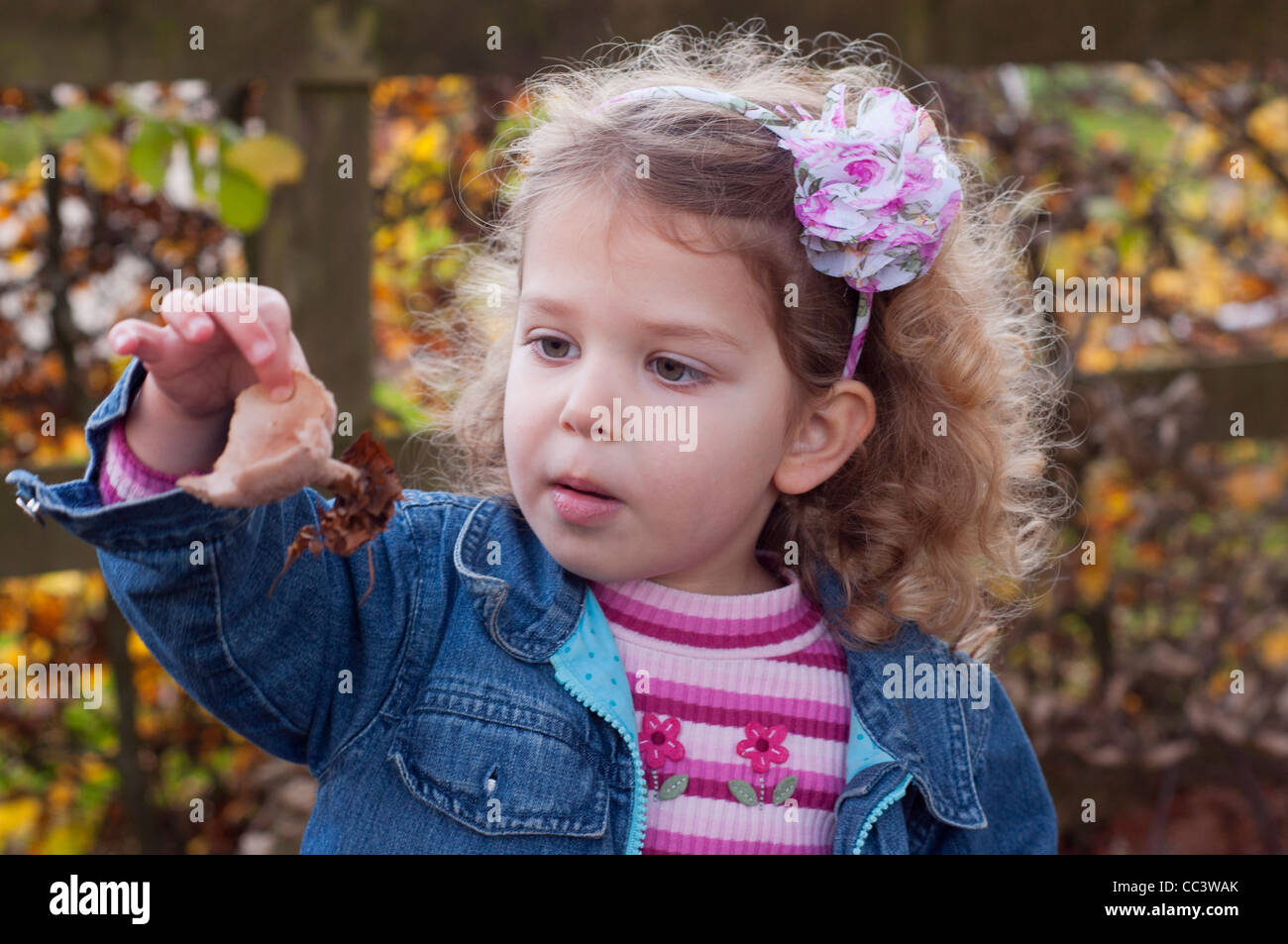 Ragazza giovane, tre anni, esplorare al di fuori. Ella è in attesa e guardando un fungo ha trovato. Foto Stock