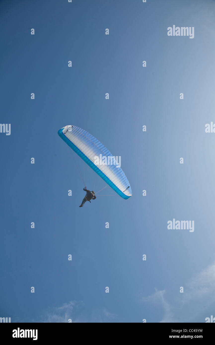 Un uomo in parapendio sotto un cielo blu chiaro Foto Stock