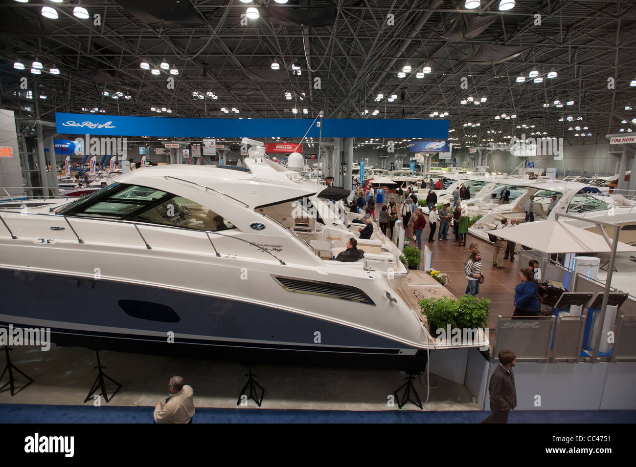 I potenziali acquirenti e persone solo navigando controllare le barche a motore al Progressive Insurance New York Boat Show Foto Stock