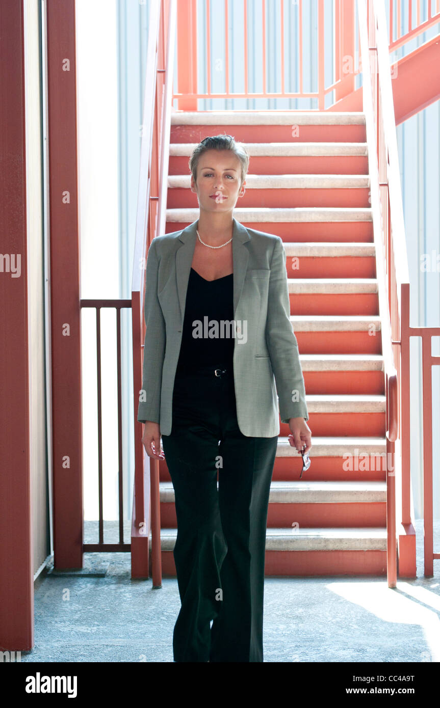 Professional Media età donna lavoratrice a piedi office vicino a scala industriale Foto Stock