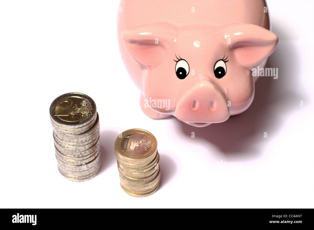 Monete in euro impilate su un tavolo con salvadanaio rosa per risparmiare  denaro. ideale per layout di siti web e riviste