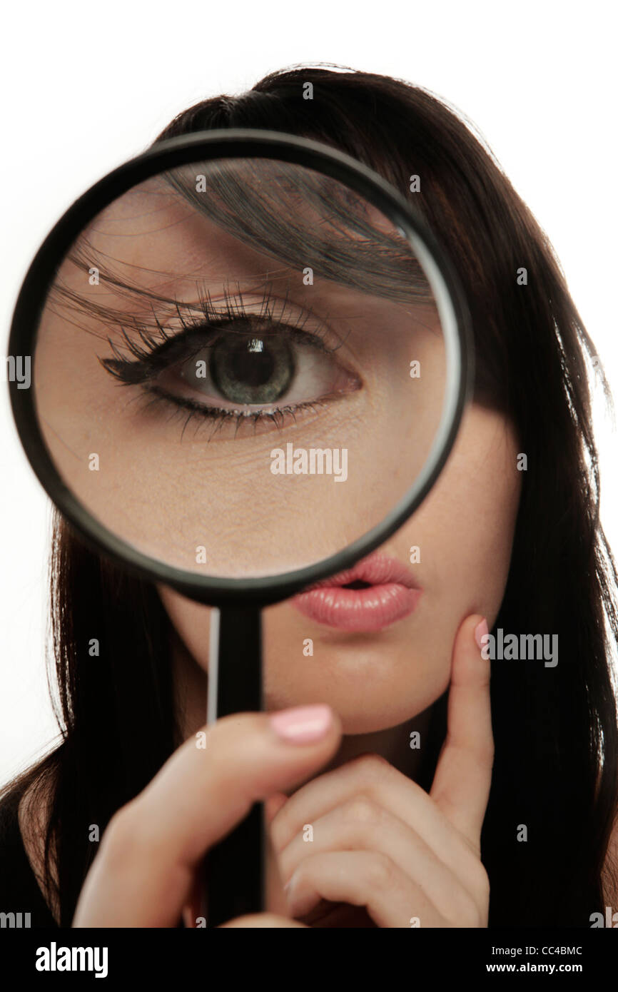 Donna che mantiene una lente di ingrandimento fino al suo occhio così sembra davvero in grande Foto Stock