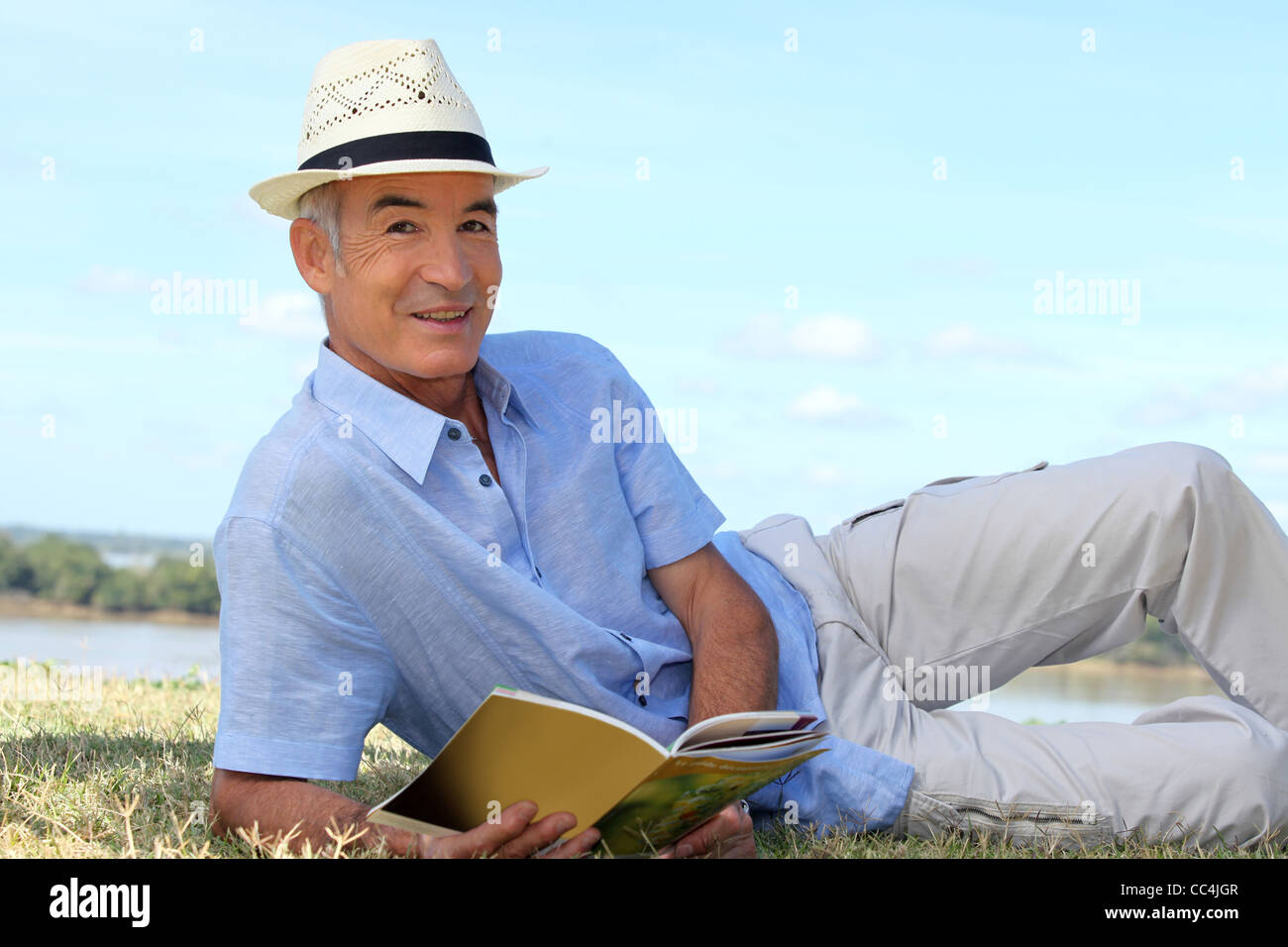 Senior lettura uomo sull'erba Foto Stock