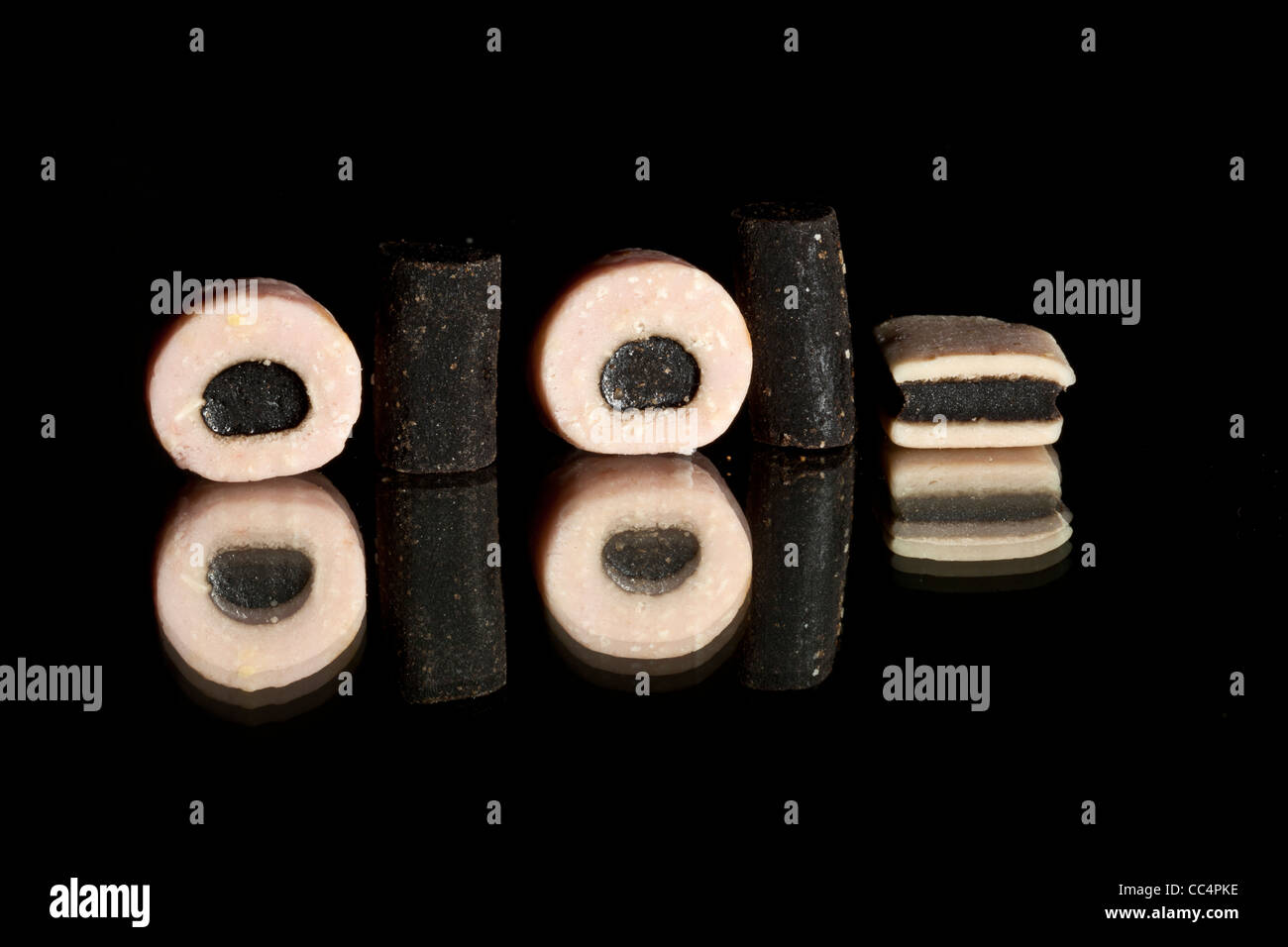 Round , Piazza e tubo allsort liquirizia caramelle su uno sfondo nero con riflessi Foto Stock