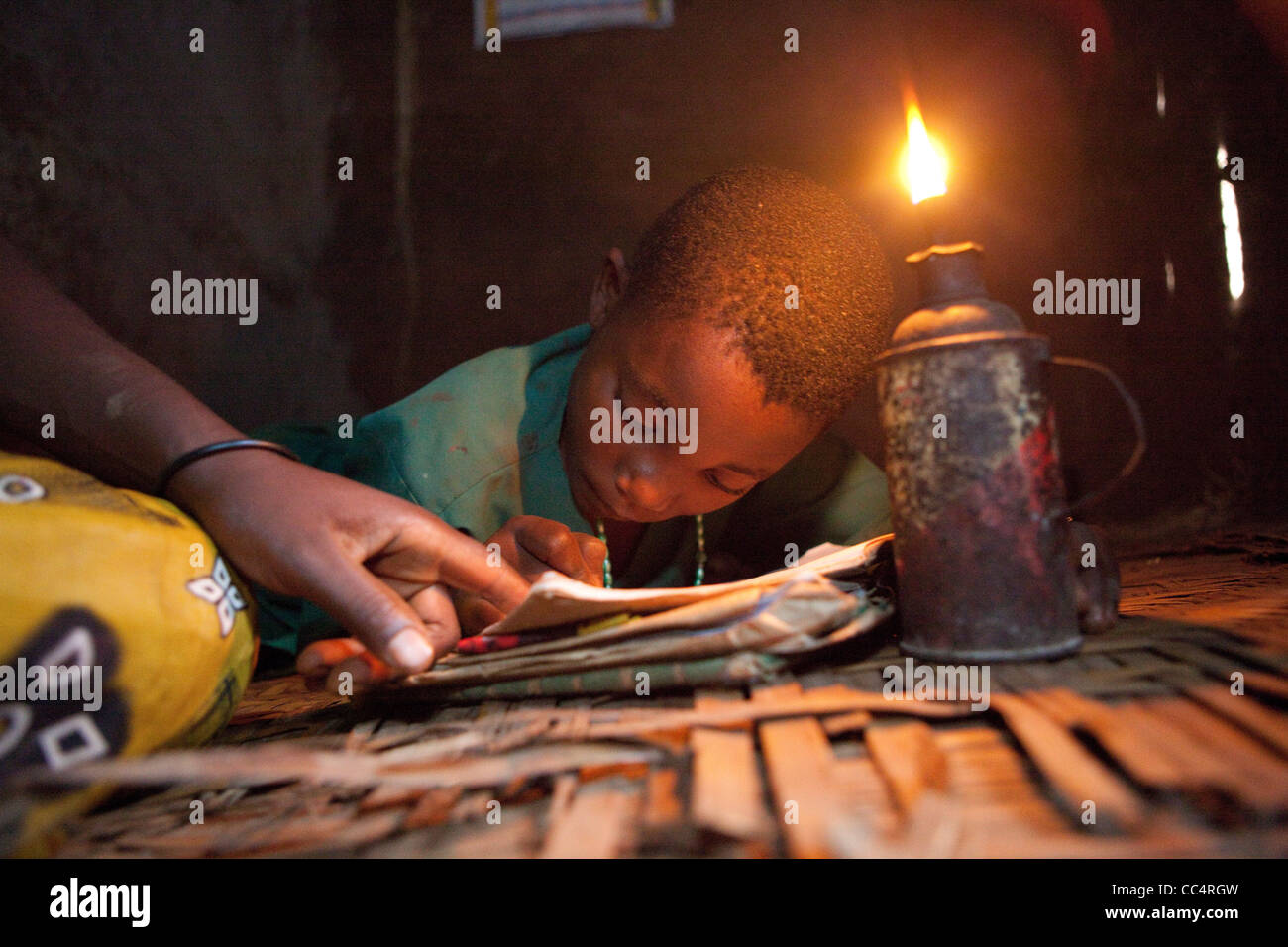 Uno studente di studi da parte di luce di una lampada di kerosene in Masaka, Uganda, Africa orientale. Foto Stock