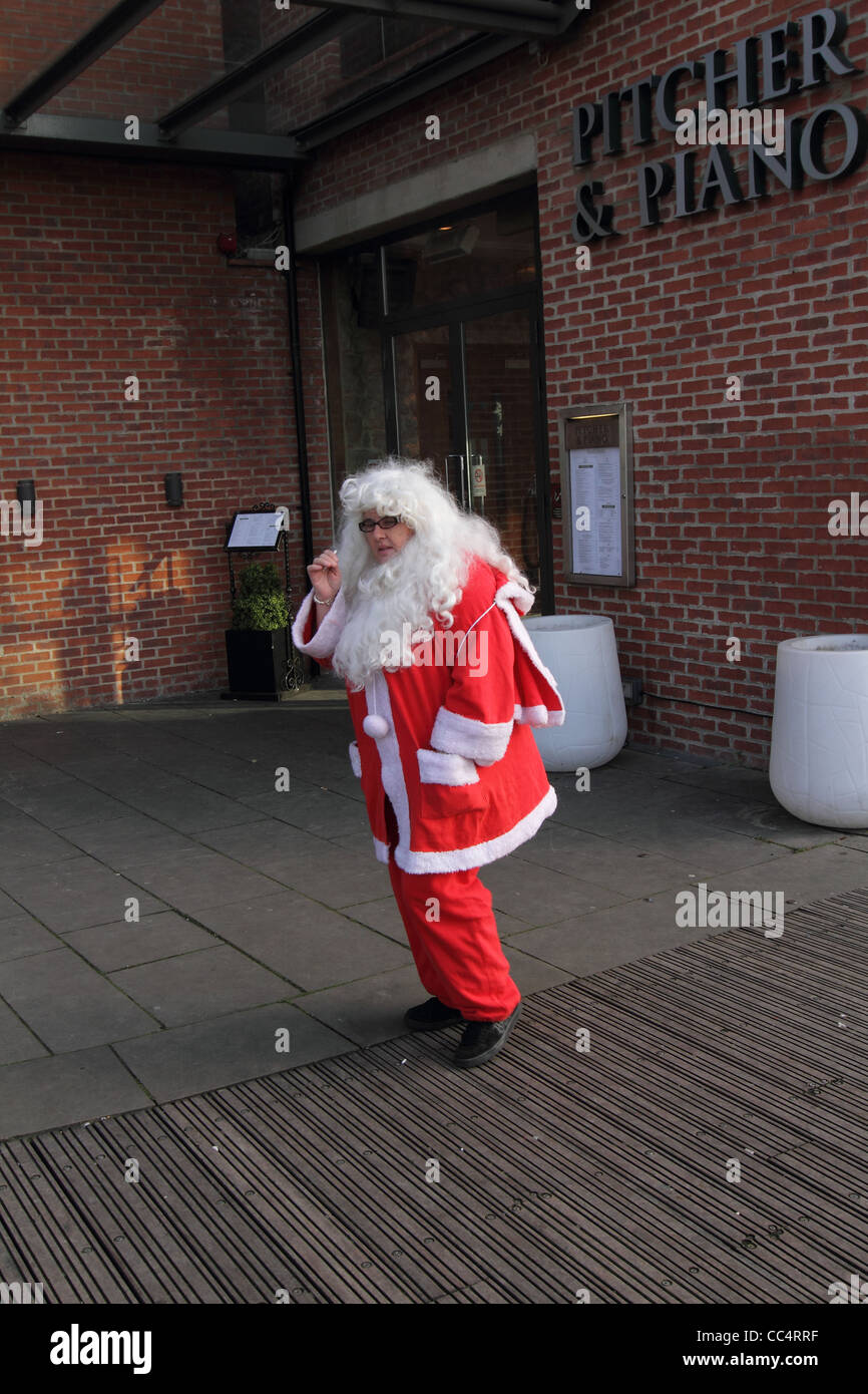 Babbo Natale, donna in santa suite avente una CIG break al di fuori del pub Foto Stock