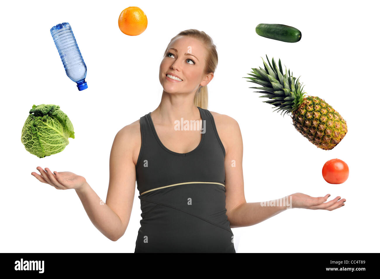 Bella giovane donna giocolare con frutta e verdura e acqua isolate su sfondo bianco Foto Stock