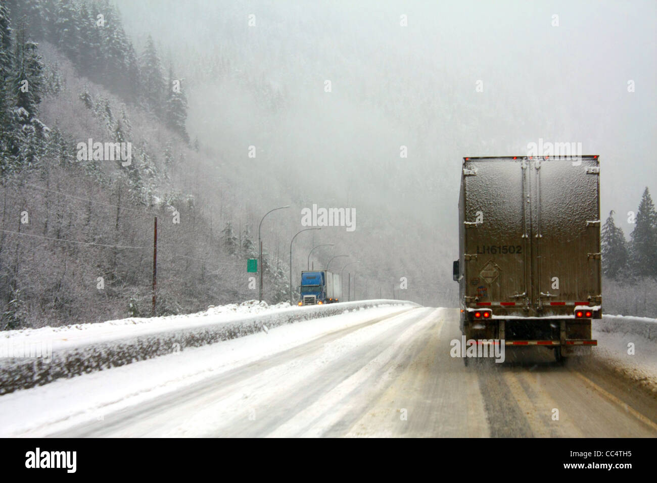 Due 40,526.02104 18 wheelers in tempesta di neve sulle slick coperta di neve 4-lane strada rurale, catene richiesto, nevicava pericolosi guida pericolosa Foto Stock