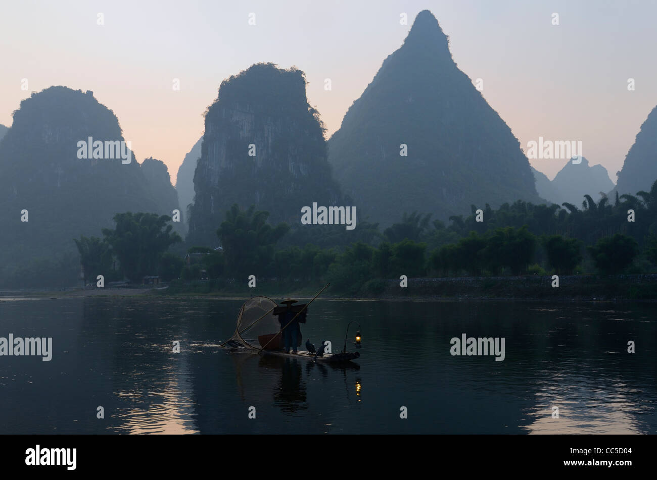 Cormorano Pescatore sul fiume Li Yangshuo con il Carso alti picchi di calcare all'alba Repubblica Popolare Cinese Foto Stock