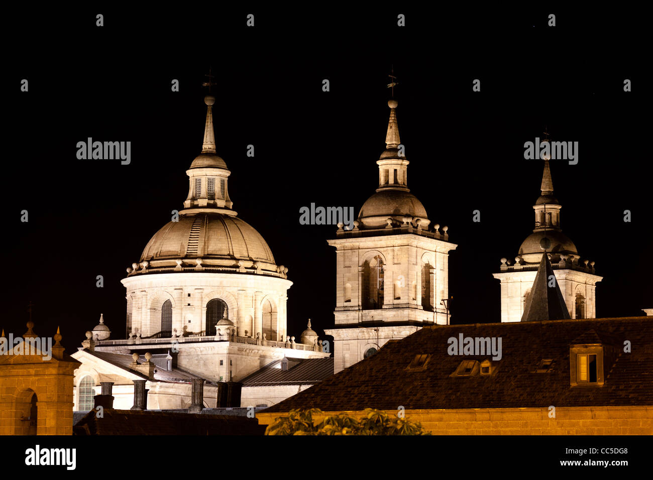 Il monastero di San Lorenzo de El Escorial di notte splendidamente illuminato. Quattro torri sono impostate su off da sfondo nero. Foto Stock