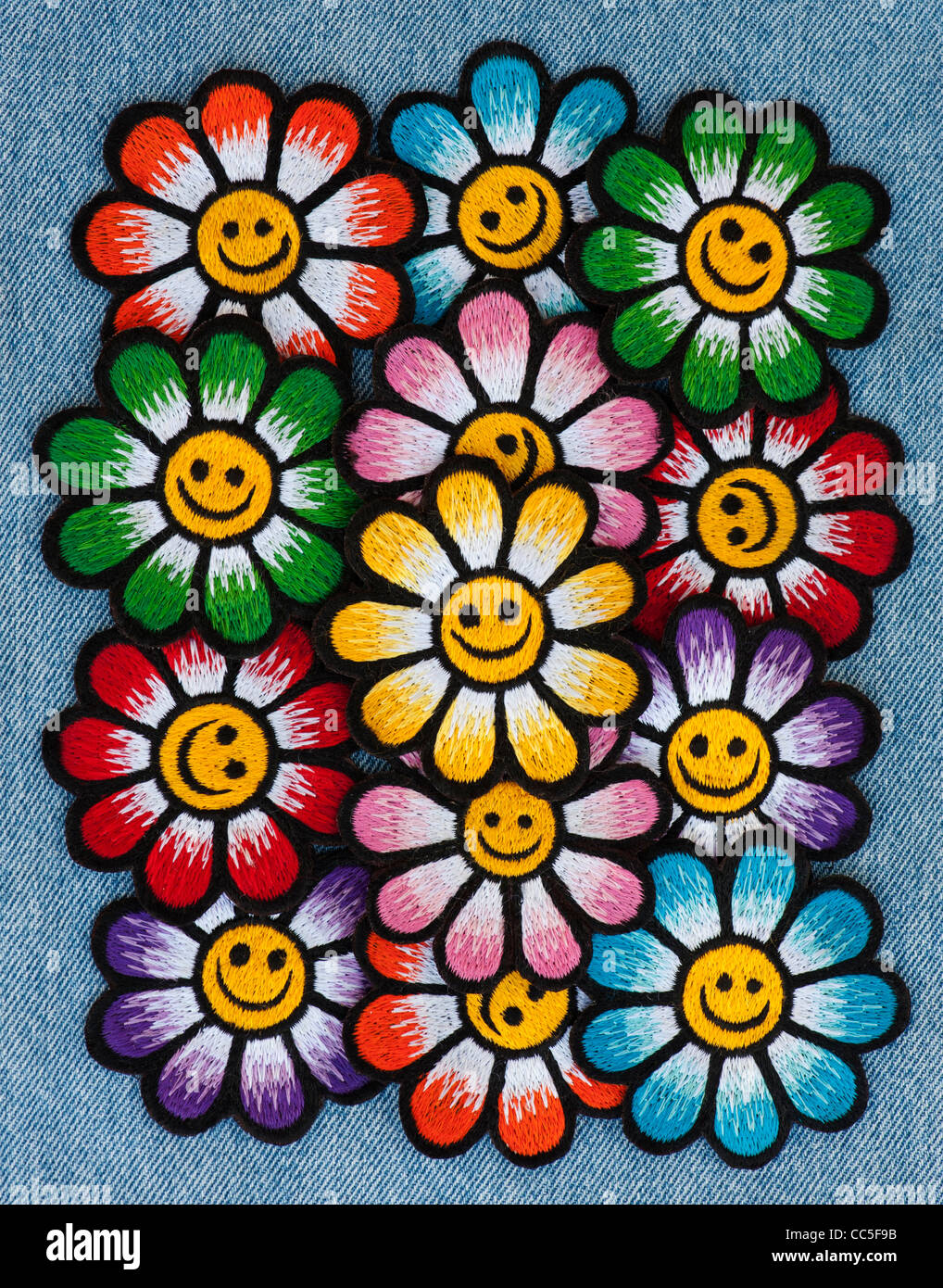 Ferro da ricamo sulle patch di variopinte Smiley face fiori su un denim jean sfondo Foto Stock