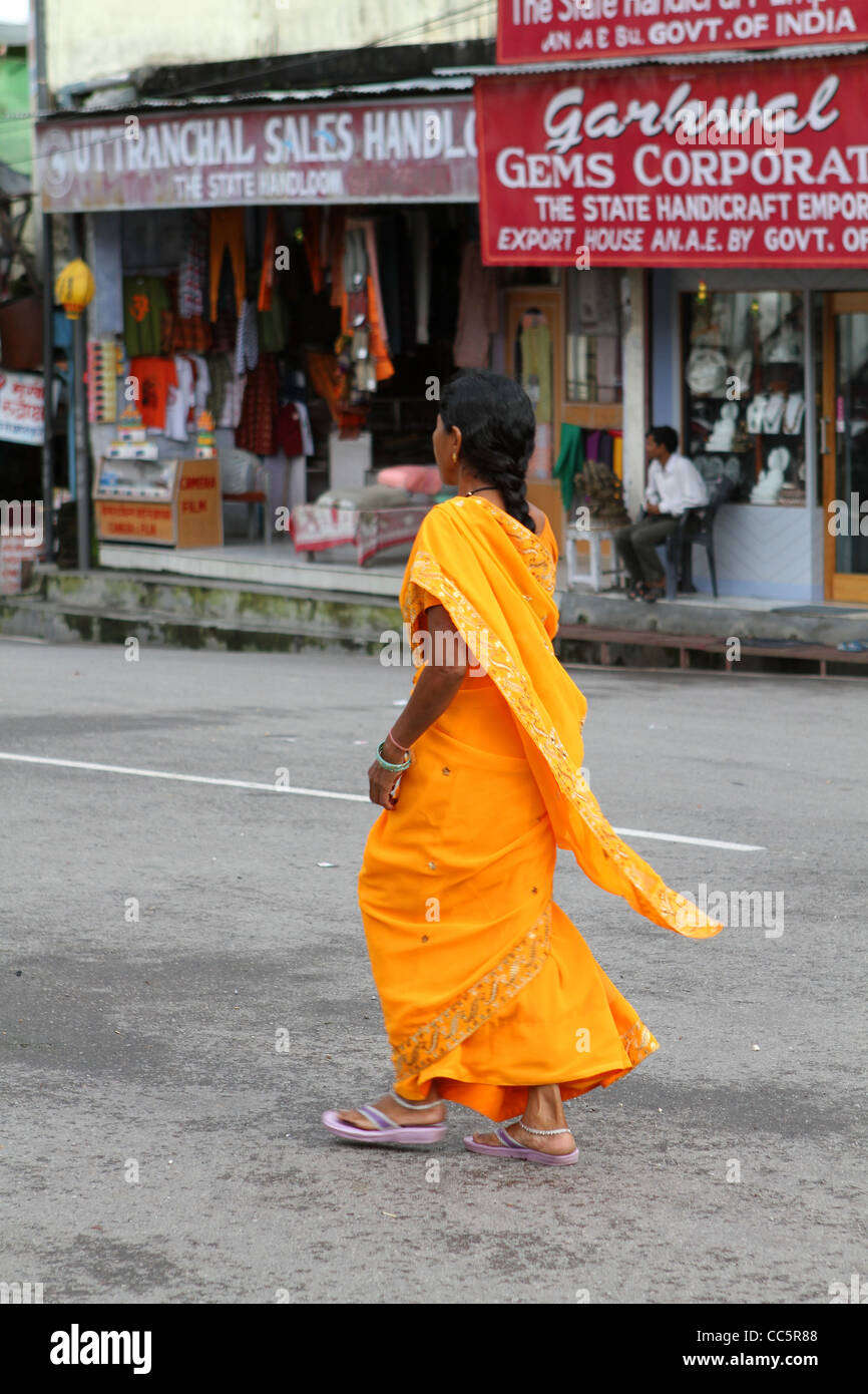 Donna indiana in arancione sari a piedi in strada. Rishikesh. India Foto Stock