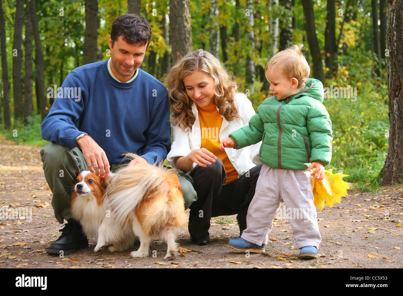 Famiglia con bambino e cane in legno di autunno Foto Stock