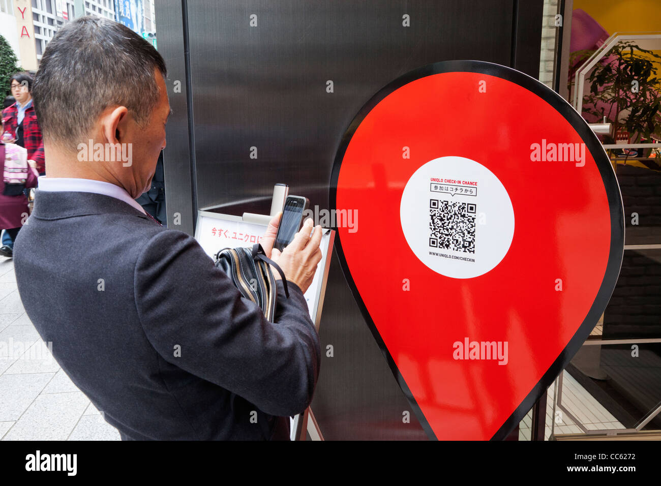 Giappone, Tokyo, Ginza, Uni Qio, Shopper fotografare il codice a barre per la concorrenza per i punti vendita Foto Stock