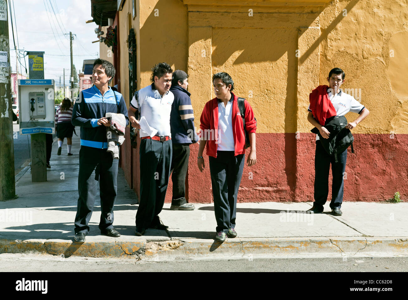 Gruppo di buon umore messicano teenage high school boys in piedi sul angolo di strada dopo la scuola nella parte anteriore della parete colorata Oaxaca Foto Stock