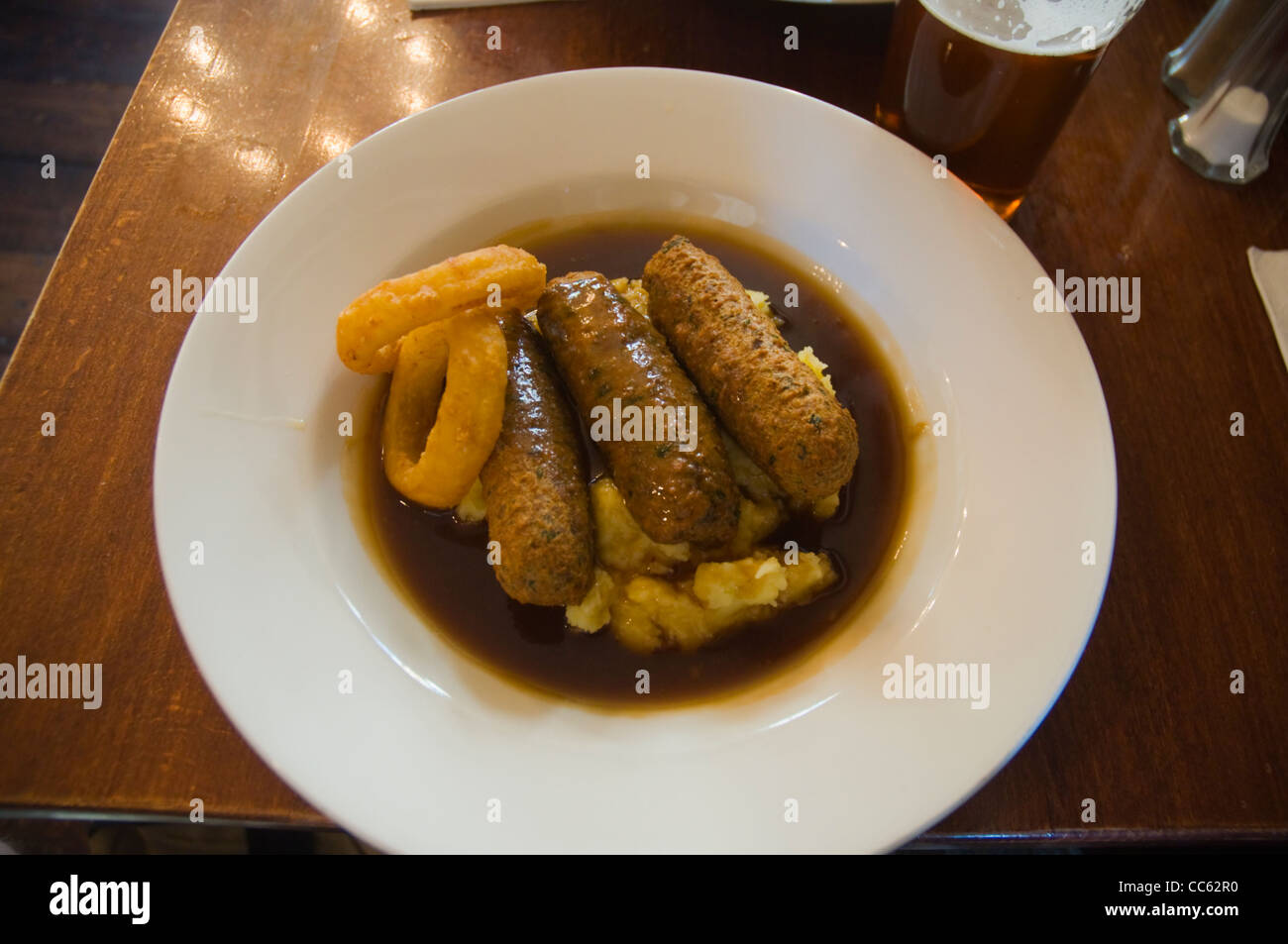 Vegetariano salsicce Cumberland e purè di patate con verdure con sugo di carne in un pub di Soho central London Inghilterra UK Europa Foto Stock