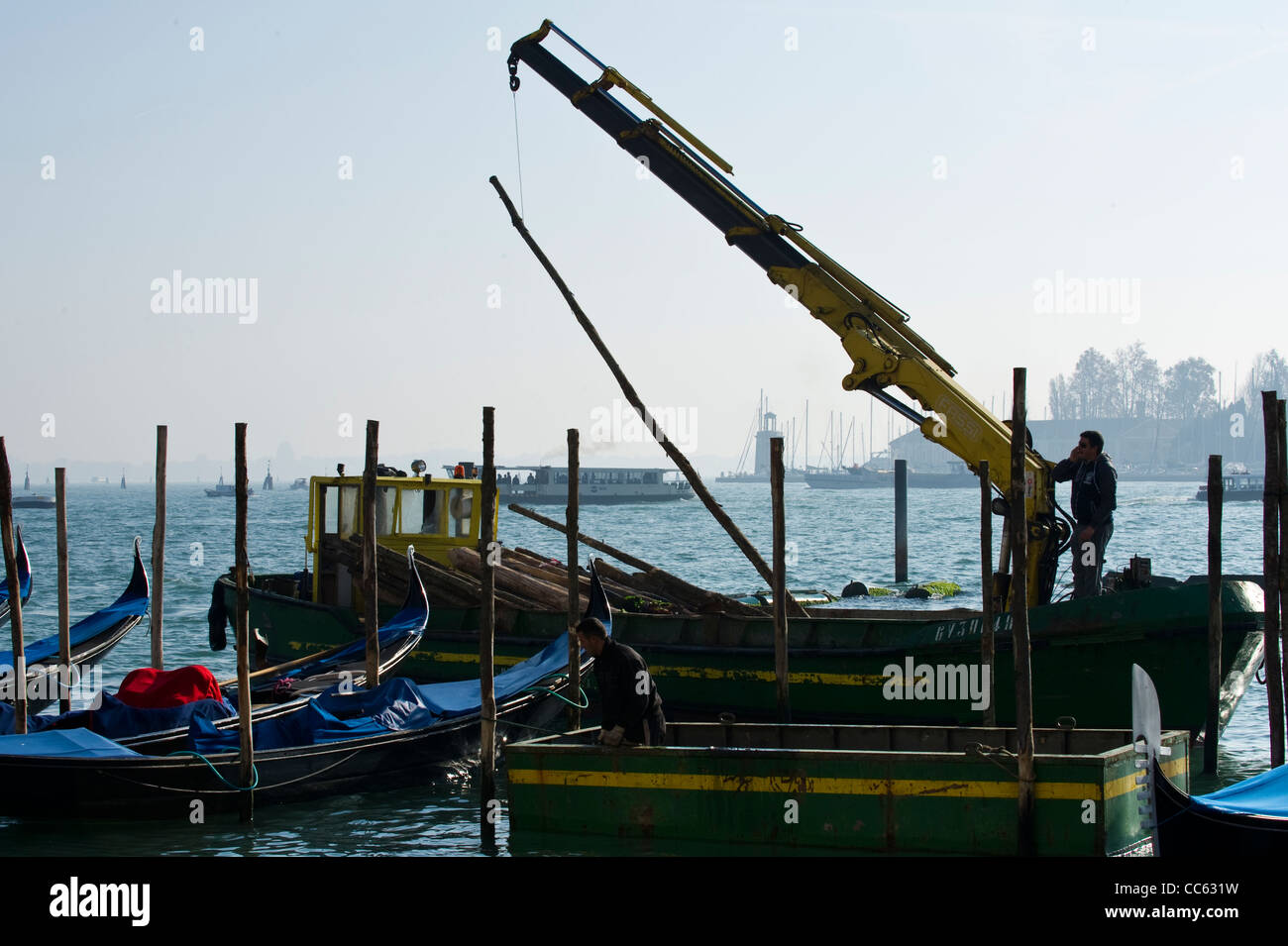 Operai la sostituzione di posti di ormeggio in laguna di Venezia - Fotografia Upix Foto Stock