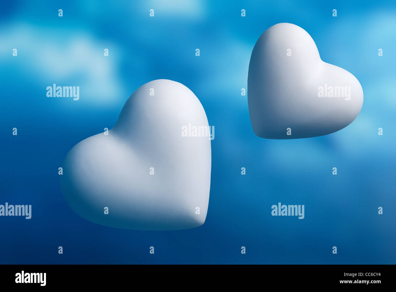 Due cuori contro un fuori fuoco cielo blu sullo sfondo Foto Stock