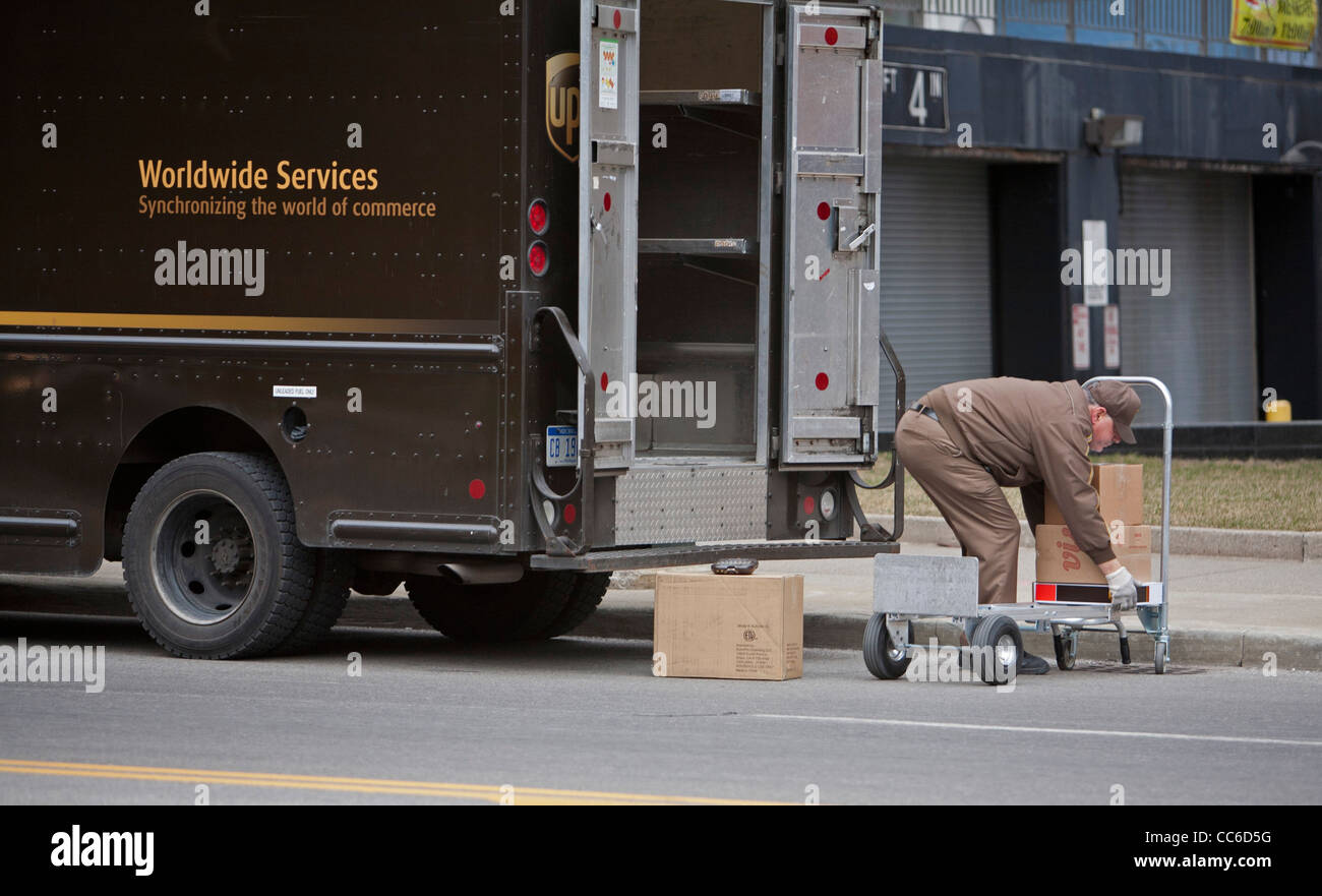 Detroit, Michigan - United Parcel Service driver pacchetti carichi nel suo carrello su una strada del centro. Foto Stock