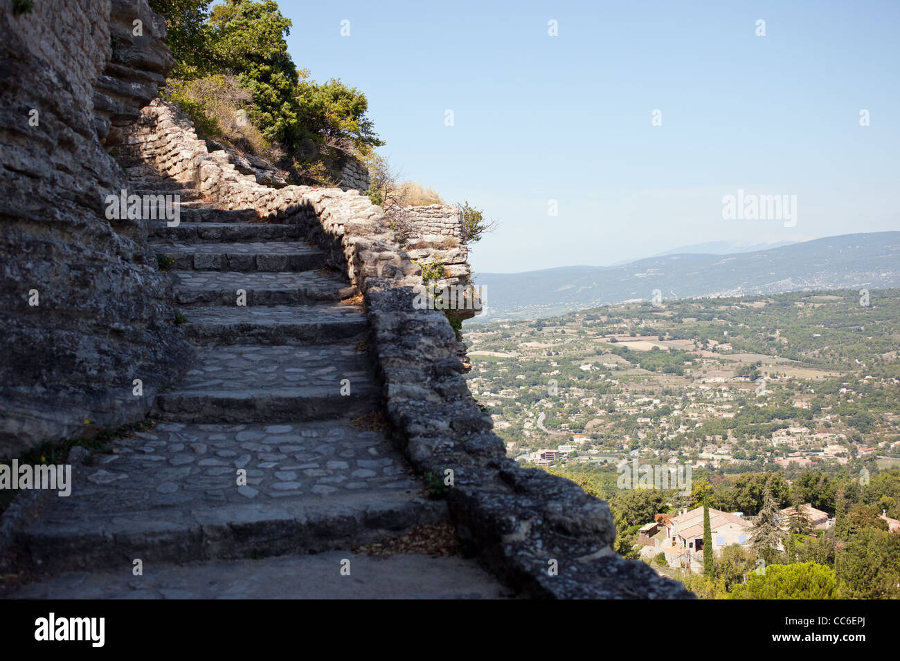 Una vecchia passerella di pietra si arrampica sul fianco di una scogliera nella bellissima città francese di Saignon Foto Stock