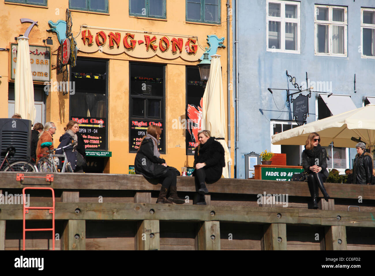 Persone in chat con ogni altro mentre è seduto sulla banca, Sluseholmen Canal District, Copenhagen, Danimarca Foto Stock