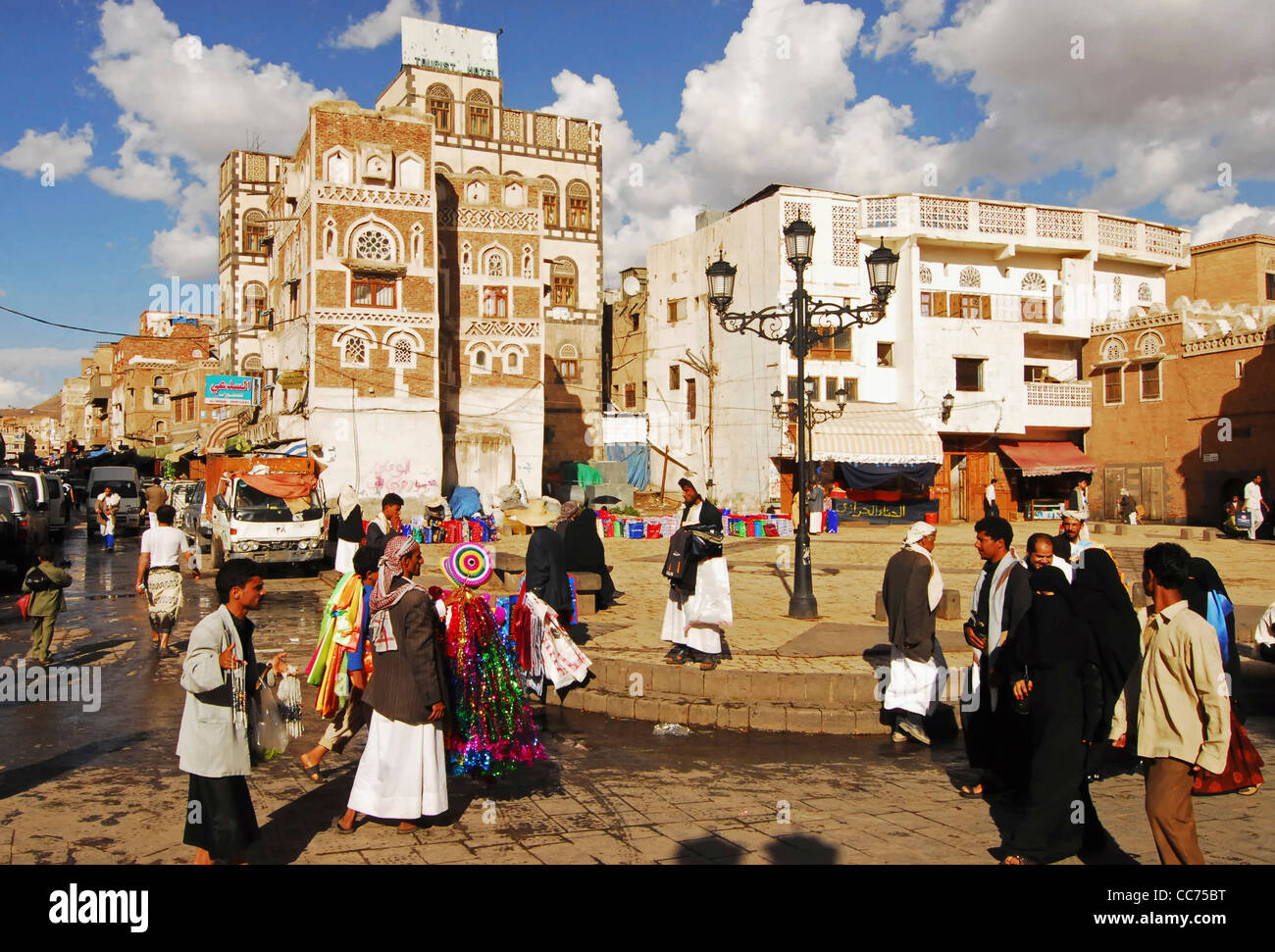 Yemen, Sanaa, occupato Market street con hawker tenendo gli articoli in vendita, gruppo di persone a piedi su strada Foto Stock